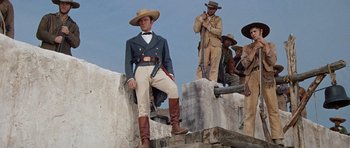 Movie still from “The Alamo” (1960), directed by John Wayne – A group of men standing next to each other on steps; Medium shot, Low angle