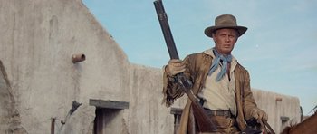 Movie still from “The Alamo” (1960), directed by John Wayne – A man holding a rifle in a cowboy outfit; Medium shot, Low angle