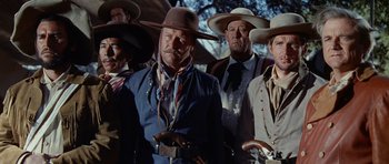 Movie still from “The Alamo” (1960), directed by John Wayne – A group of men standing next to each other wearing cowboy hats; Medium shot, Low angle
