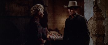 Movie still from “The Alamo” (1960), directed by John Wayne – A man and a woman talking in a dark room; Medium shot, Over the shoulder angle