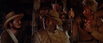 Movie still from “The Alamo” (1960), directed by John Wayne – A man in a hat and a vest holding a rifle; Medium shot, Low angle