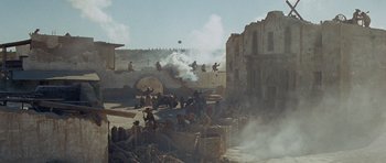 Movie still from “The Alamo” (1960), directed by John Wayne – A group of people sitting on top of a pile of rocks; Extreme Wide shot, High angle