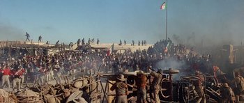 Movie still from “The Alamo” (1960), directed by John Wayne – A group of people standing around a fence; Extreme Wide shot, Low angle