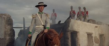 Movie still from “The Alamo” (1960), directed by John Wayne – A man riding a horse with other men on top of it; Medium shot, Low angle