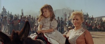 Movie still from “The Alamo” (1960), directed by John Wayne – A little girl sitting on the back of a horse in front of a crowd; Close Up shot, Low angle