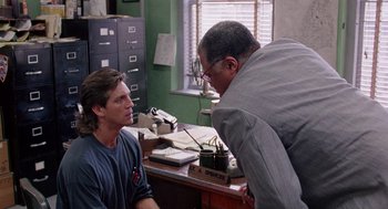 Movie still from “The Ambulance” (1990), directed by Larry Cohen – A man and a woman are talking in an office setting; Medium shot, Over the shoulder angle