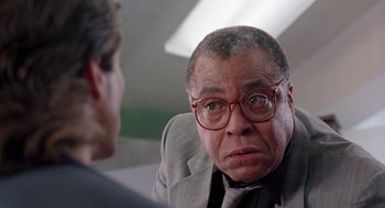 Movie still from “The Ambulance” (1990), directed by Larry Cohen – An older man wearing glasses and a suit and tie; Close Up shot, Over the shoulder angle