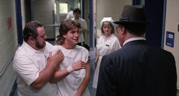 Movie still from “The Ambulance” (1990), directed by Larry Cohen – A group of people standing next to each other in a room; Medium shot, Over the shoulder angle