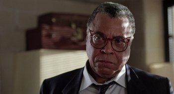 Movie still from “The Ambulance” (1990), directed by Larry Cohen – An older man wearing a suit and red glasses; Close Up shot, Low angle