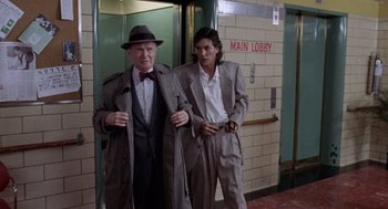 Movie still from “The Ambulance” (1990), directed by Larry Cohen – A man and a woman dressed up in suits and hats; Medium shot, Low angle