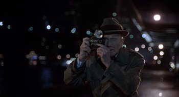 Movie still from “The Ambulance” (1990), directed by Larry Cohen – An older man taking a picture with a camera; Close Up shot, High angle
