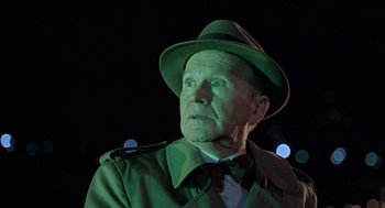 Movie still from “The Ambulance” (1990), directed by Larry Cohen – An old man wearing a hat and a green coat; Close Up shot, Low angle
