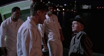 Movie still from “The Ambulance” (1990), directed by Larry Cohen – A group of men standing next to each other on a dock; Medium shot, Over the shoulder angle