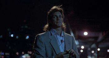 Movie still from “The Ambulance” (1990), directed by Larry Cohen – A man in a suit standing in front of a building; Medium shot, Low angle
