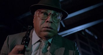 Movie still from “The Ambulance” (1990), directed by Larry Cohen – A man in a suit and tie holding a gun; Close Up shot, Low angle