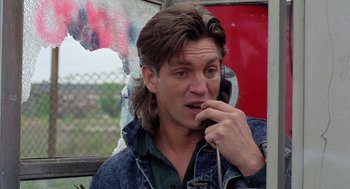 Movie still from “The Ambulance” (1990), directed by Larry Cohen – A man talking on a cell phone while wearing a jean jacket; Close Up shot, Low angle