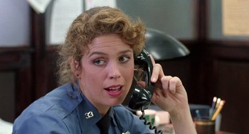 Movie still from “The Ambulance” (1990), directed by Larry Cohen – A police officer talking on a phone while sitting at a desk; Close Up shot, Over the shoulder angle