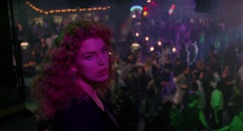 A woman with red curly hair standing in front of a crowd of people