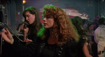 Movie still from “The Ambulance” (1990), directed by Larry Cohen – A woman with long red curly hair is standing next to another woman with long red hair; Medium shot, Over the shoulder angle