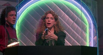 Movie still from “The Ambulance” (1990), directed by Larry Cohen – A woman with curly hair is holding a video game controller; Medium shot, Low angle