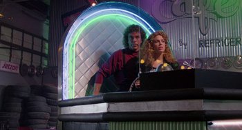 Movie still from “The Ambulance” (1990), directed by Larry Cohen – A man and a woman are standing in front of a bar; Medium shot, Low angle