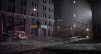 Movie still from “The Ambulance” (1990), directed by Larry Cohen – A city street at night with buildings lit by street lights; Extreme Wide shot, High angle