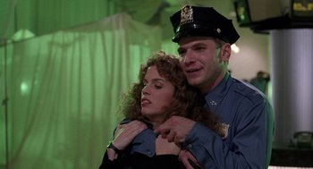 Movie still from “The Ambulance” (1990), directed by Larry Cohen – A man and a woman in police uniforms hugging each other; Medium shot, Low angle
