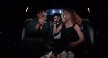 Movie still from “The Ambulance” (1990), directed by Larry Cohen – A man and a woman sitting in a car holding wine glasses; Medium shot, Low angle