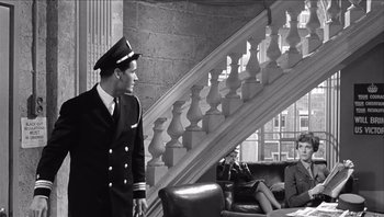 Movie still from “The Americanization of Emily” (1964), directed by Arthur Hiller – A man in a uniform standing in front of a staircase; Wide shot, Low angle