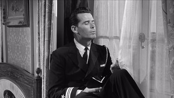 Movie still from “The Americanization of Emily” (1964), directed by Arthur Hiller – A black and white photo of a man in a suit and tie; Medium shot, Low angle