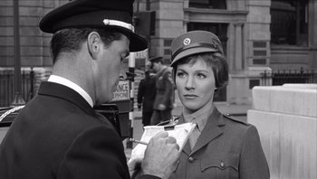 Movie still from “The Americanization of Emily” (1964), directed by Arthur Hiller – A woman in a military uniform is being interviewed by a man in a uniform; Medium shot, Over the shoulder angle