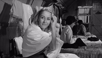 Movie still from “The Americanization of Emily” (1964), directed by Arthur Hiller – A woman sitting on a chair in front of a group of people; Close Up shot, Over the shoulder angle