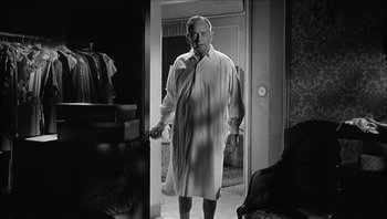 Movie still from “The Americanization of Emily” (1964), directed by Arthur Hiller – A black and white photo of a man standing in front of a door; Medium shot, Low angle