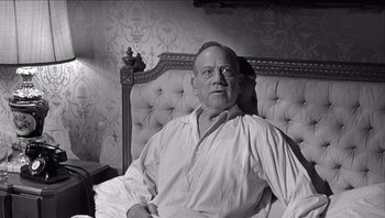 Movie still from “The Americanization of Emily” (1964), directed by Arthur Hiller – An older man sitting on a couch in a room; Medium shot, High angle