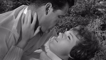 Movie still from “The Americanization of Emily” (1964), directed by Arthur Hiller – A man and a young girl laying in the grass; Close Up shot, High angle
