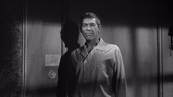 Movie still from “The Americanization of Emily” (1964), directed by Arthur Hiller – Black and white photograph of a man standing in front of a door; Medium shot, Low angle
