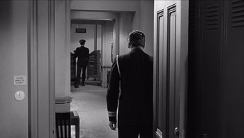 Movie still from “The Americanization of Emily” (1964), directed by Arthur Hiller – A man walking down a hall way in a room; Wide shot, High angle
