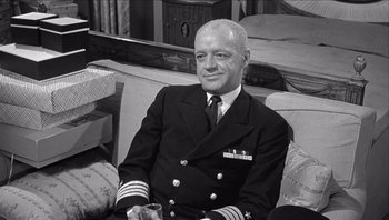 Movie still from “The Americanization of Emily” (1964), directed by Arthur Hiller – An older man in a naval uniform sitting on a couch; Medium shot, High angle