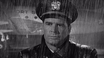 Movie still from “The Americanization of Emily” (1964), directed by Arthur Hiller – A black and white photo of a man in a uniform in the rain; Close Up shot, Low angle