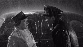 Movie still from “The Americanization of Emily” (1964), directed by Arthur Hiller – Two men in uniform talking in the rain in a car; Medium shot, High angle