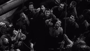 Movie still from “The Americanization of Emily” (1964), directed by Arthur Hiller – A group of men holding onto a rope and smiling; Wide shot, Overhead angle
