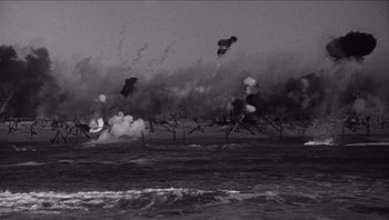 Movie still from “The Americanization of Emily” (1964), directed by Arthur Hiller – A black and white photo of an ocean with smoke coming out of it; Extreme Wide shot, High angle
