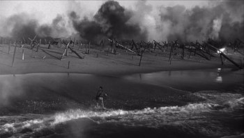 Movie still from “The Americanization of Emily” (1964), directed by Arthur Hiller – Black and white photograph of a man on a surfboard in the ocean; Extreme Wide shot, High angle