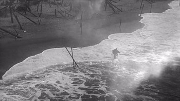 Movie still from “The Americanization of Emily” (1964), directed by Arthur Hiller – A person standing in the surf of the ocean; Extreme Wide shot, High angle