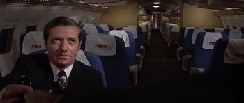 Movie still from “The Andromeda Strain” (1971), directed by Robert Wise – A man wearing a suit and tie sitting in an airplane; Medium shot, High angle