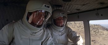 Movie still from “The Andromeda Strain” (1971), directed by Robert Wise – Two men in white suits and helmets in a helicopter; Medium shot, High angle