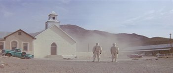Movie still from “The Andromeda Strain” (1971), directed by Robert Wise – Two men in white suits standing in front of a church; Extreme Wide shot, Low angle