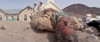 Movie still from “The Andromeda Strain” (1971), directed by Robert Wise – An old man laying on the ground with two people standing around him; Wide shot, Low angle