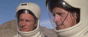 Movie still from “The Andromeda Strain” (1971), directed by Robert Wise – Two men in spacesuits looking at each other in the desert; Close Up shot, Low angle