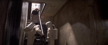 Movie still from “The Andromeda Strain” (1971), directed by Robert Wise – Two men in white suits and a woman in a black dress are climbing up the stairs; Wide shot, Low angle